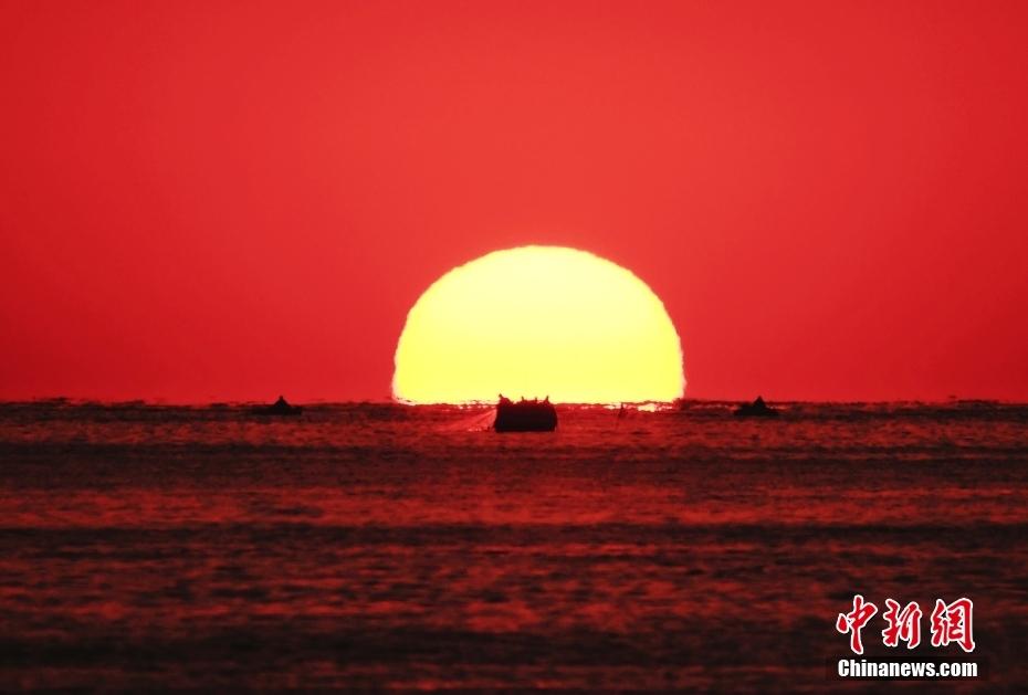 2023年国庆节当天，青岛海上日出，火红的朝霞中，海面上的船只仿佛正漂向太阳。图片来源：视觉中国