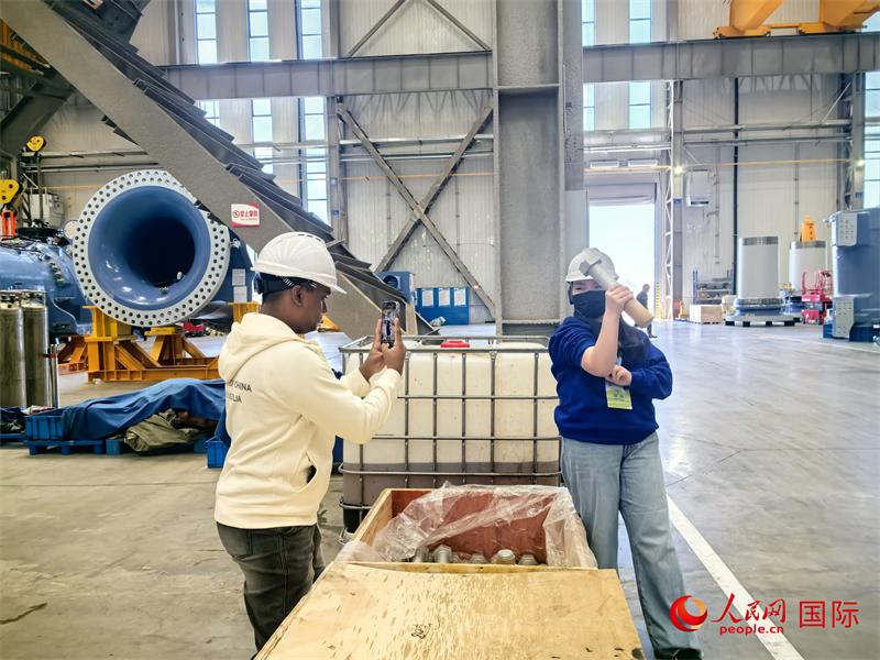 外媒记者掂量厂房内的巨型螺栓。人民网 杨春燕摄