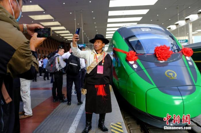 2021年6月25日,川藏铁路拉林段(拉林铁路)正式开通运营,复兴号高原内电双源动车组同步投入运营。拉林铁路全长48公里,设计时速160公里。这是西藏首条电气化铁路,也是复兴号动车组首次开进西藏。图为当日,民众在拉萨火车站复兴号车头前拍照留念。 <a target='_blank' href='/'>中新社</a>记者 江飞波 摄